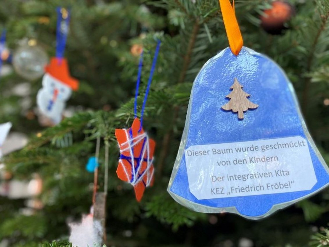 Eine gebastelte Glocke aus Papier hängt am Weihnachtsbaum