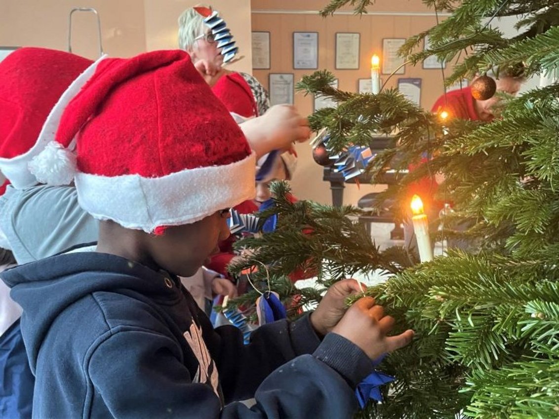 Kinder hängen Weihnachtsbaumschmuck an