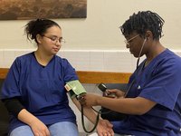 Zwei Auszubildende, die Blutdruckmessen üben