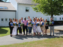 Gruppenfoto der 14 Absolventinnen und Absolventen der Pflegeschule des AMEOS Instituts West vor dem Schulgebäude