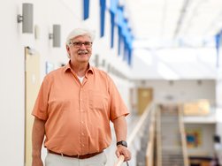 Hans-Ulrich Wenig nach seinem Aufenthalt im AMEOS Klinikum Eutin. Er blickt freundlich in die Kamera und steht in der Galerie des Klinikums (© AMEOS).