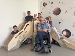 Sensorische Spielecke mit 3 Kindern und 2 Pflegefachkräften sowie dem Chefarzt im Rollstuhl.