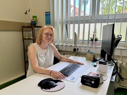 Ärztin sitzt am Schreibtisch und lächelt in die Kamera